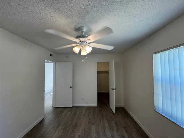 an empty room with wooden floor and ceiling fan