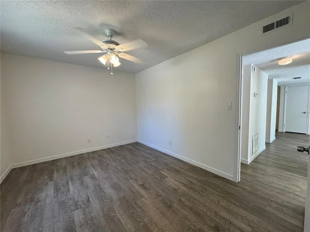a view of a room with wooden floor and a ceiling fan