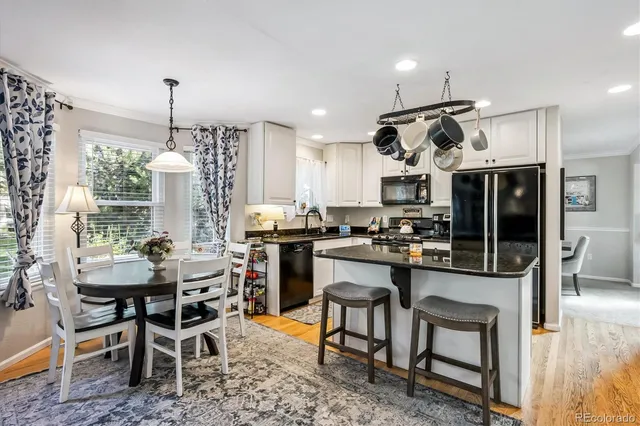 a kitchen with stainless steel appliances kitchen island granite countertop a table chairs sink and cabinets