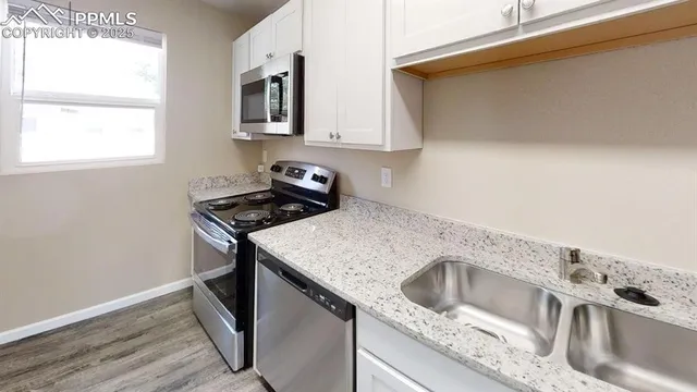 a kitchen with granite countertop a sink a stove and wooden floor