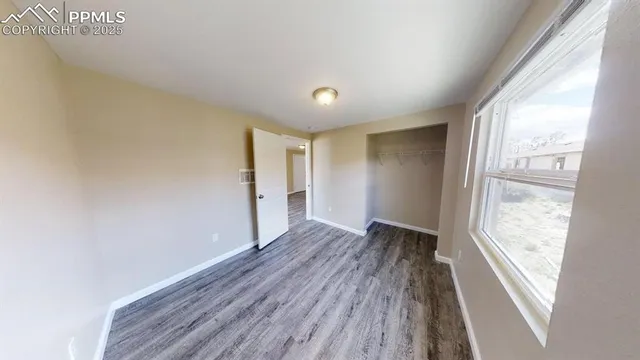 a view of an empty room with wooden floor and a window