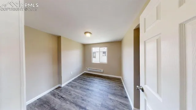 a view of an empty room with wooden floor and a window