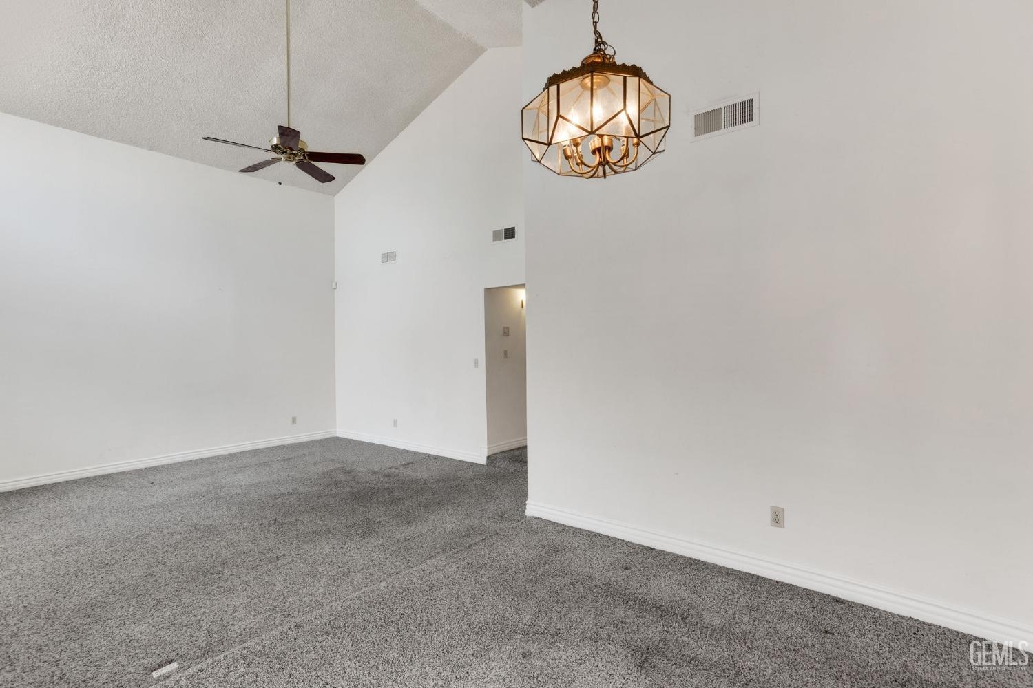 Undisclosed Address Bakersfield, CA 93306 - Photo 13 of 51 an empty room with a chandelier fan and wooden floor