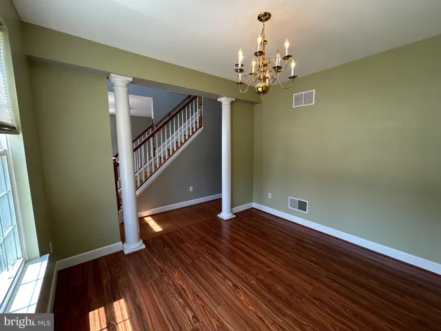 a view of an empty room with wooden floor and staircase