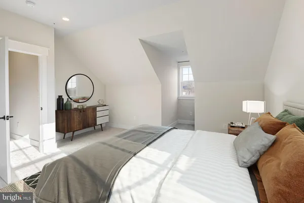 a bedroom with a bed large mirror and a lamp on dresser