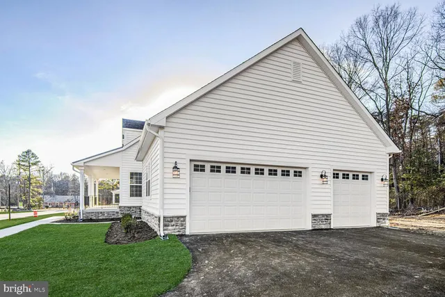 a view of a white house next to a yard with big trees