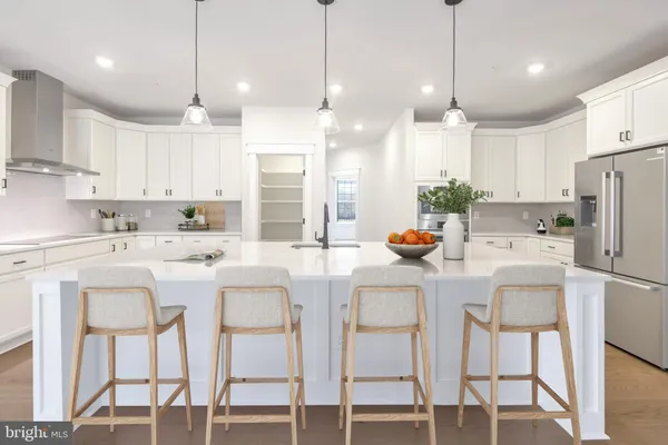 a kitchen with stainless steel appliances kitchen island granite countertop a dining table chairs and white cabinets