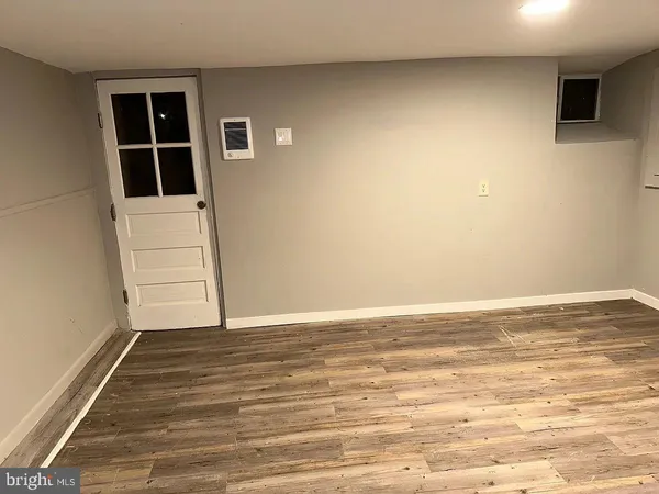 a view of an empty room with wooden floor and windows
