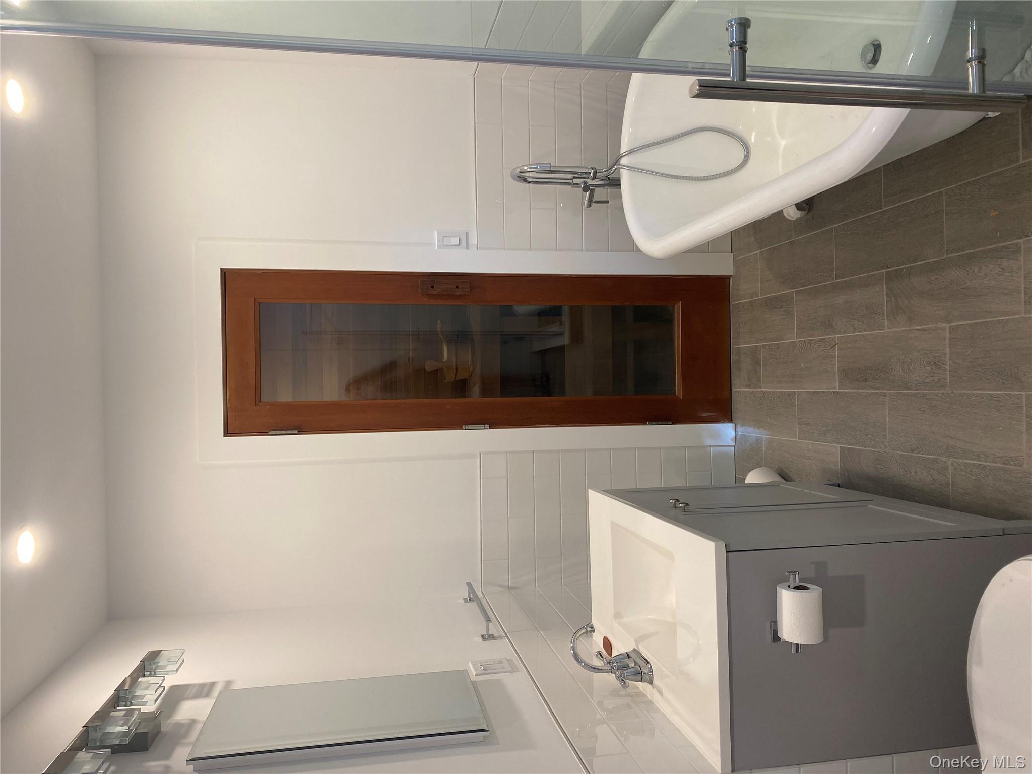 98 Travis Corners Road Garrison, NY 10524 - Photo 11 of 17 Full bath with tile walls, vanity, a soaking tub, a wainscoted wall, and a relaxing sauna