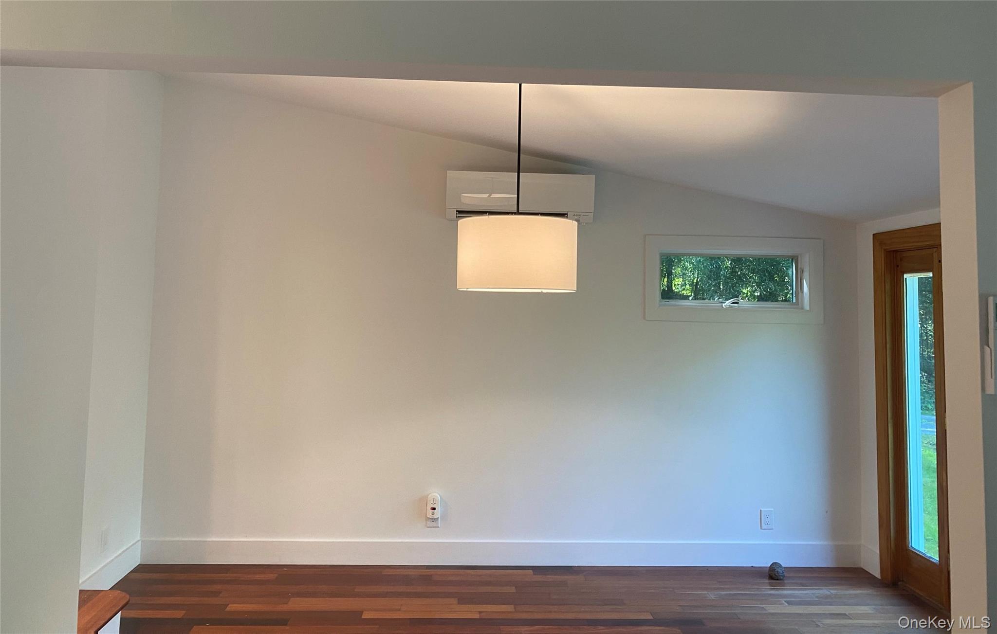 98 Travis Corners Road Garrison, NY 10524 - Photo 5 of 17 Unfurnished dining area featuring vaulted ceiling, an AC wall unit, and dark wood-type flooring