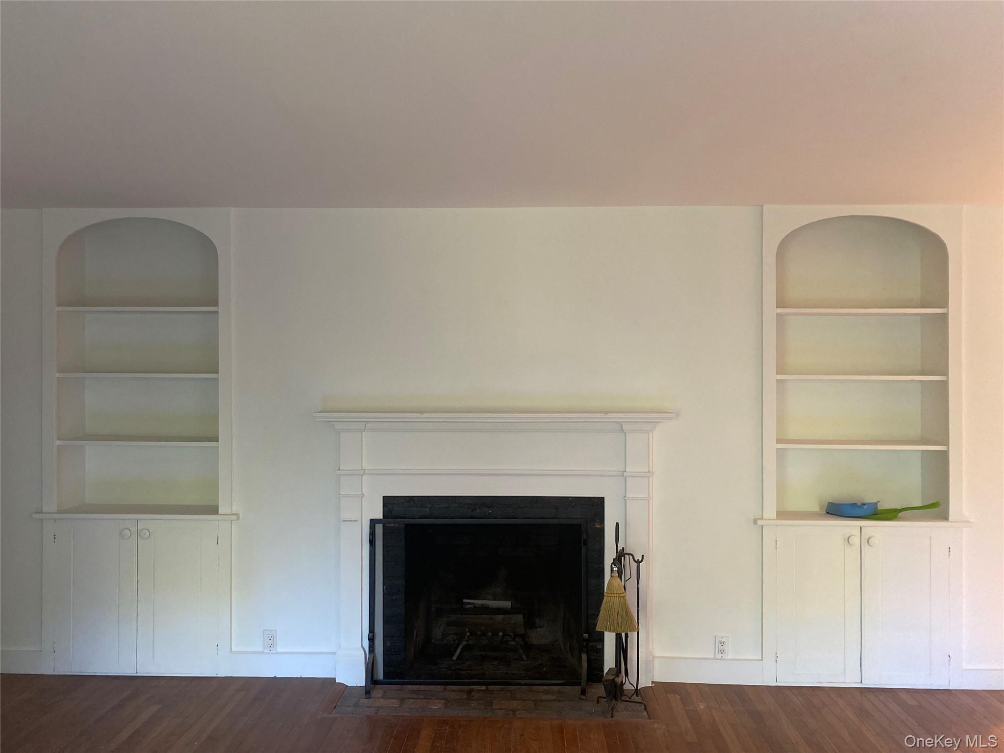 98 Travis Corners Road Garrison, NY 10524 - Photo 7 of 17 Living area with built in features, dark wood-style flooring, and a fireplace with flush hearth