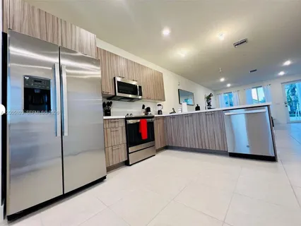 a kitchen with stainless steel appliances granite countertop a refrigerator and a view of living room