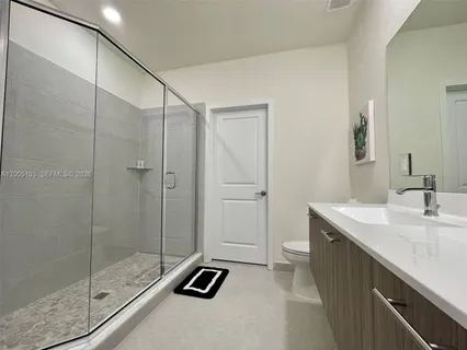 a bathroom with a toilet a sink a mirror and a shower