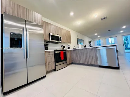 a kitchen with stainless steel appliances granite countertop a refrigerator and a view of living room