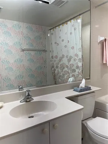 a bathroom with a sink and mirror with toilet