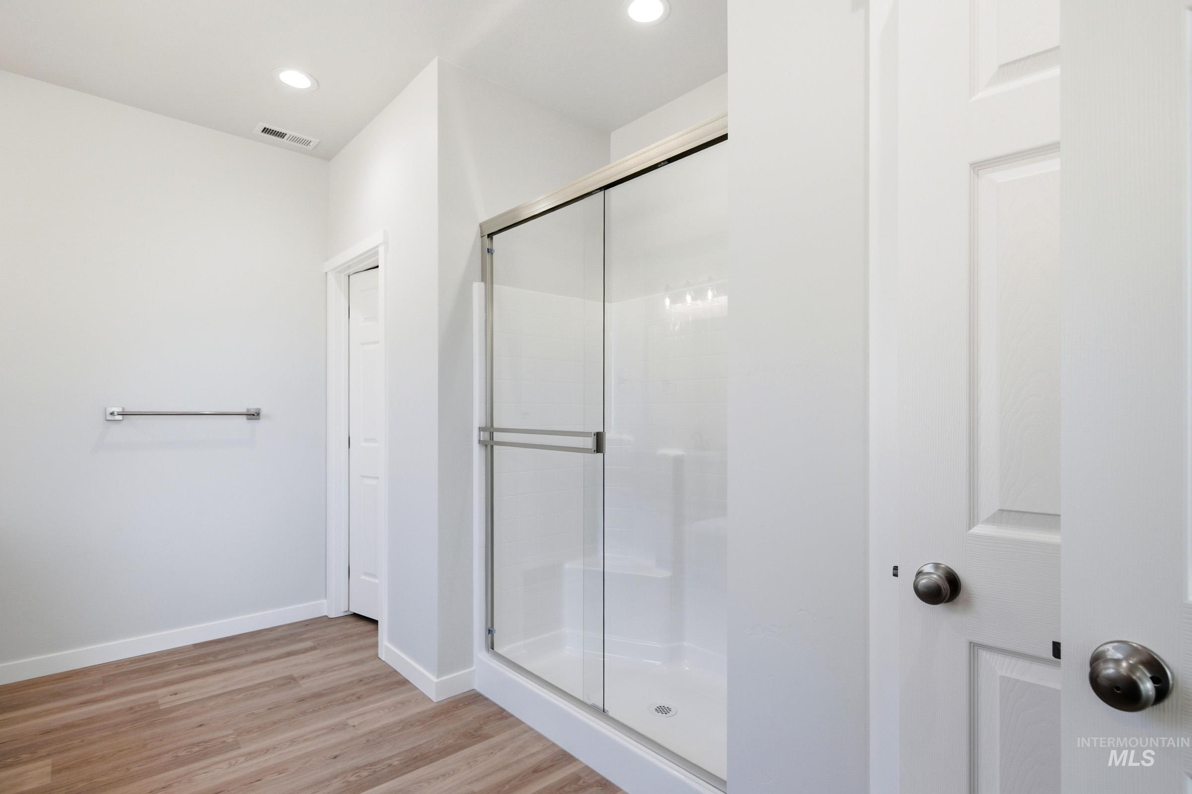 13649 Inman Court Caldwell, ID 83607 - Photo 22 of 22 Bathroom featuring a glass-enclosed shower with a stainless steel frame, wood-finish flooring, recessed lighting, and a chrome towel bar