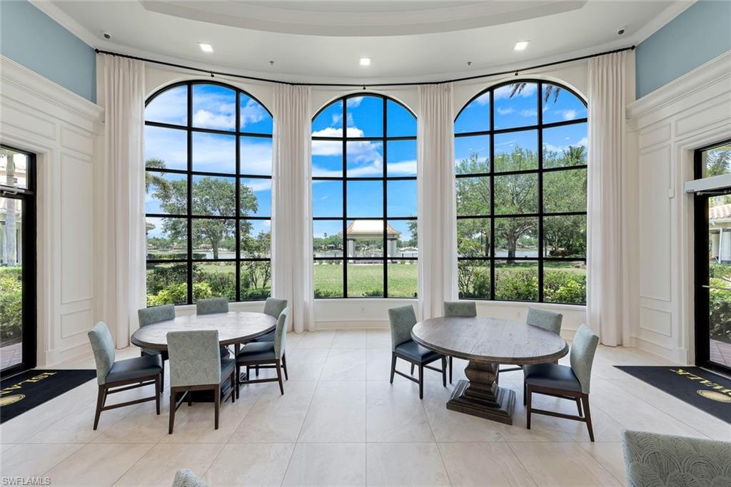 3108 Dominica Way Naples, FL 34119 - Photo 29 of 39 Towncenter grand room featuring three arched windows with black grid frames, extensive white wainscoting, and light-toned tile flooring