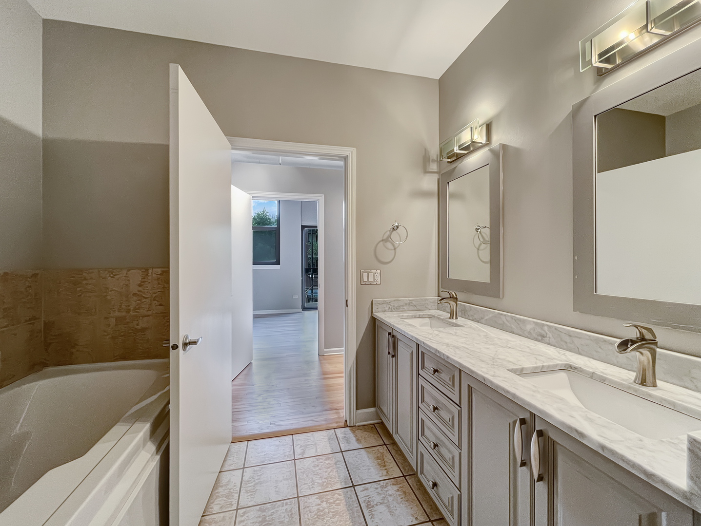 1301 West Madison Street, Unit 201 Chicago, IL 60607 - Photo 11 of 14 a spacious bathroom with a double vanity sink a mirror and a bathtub