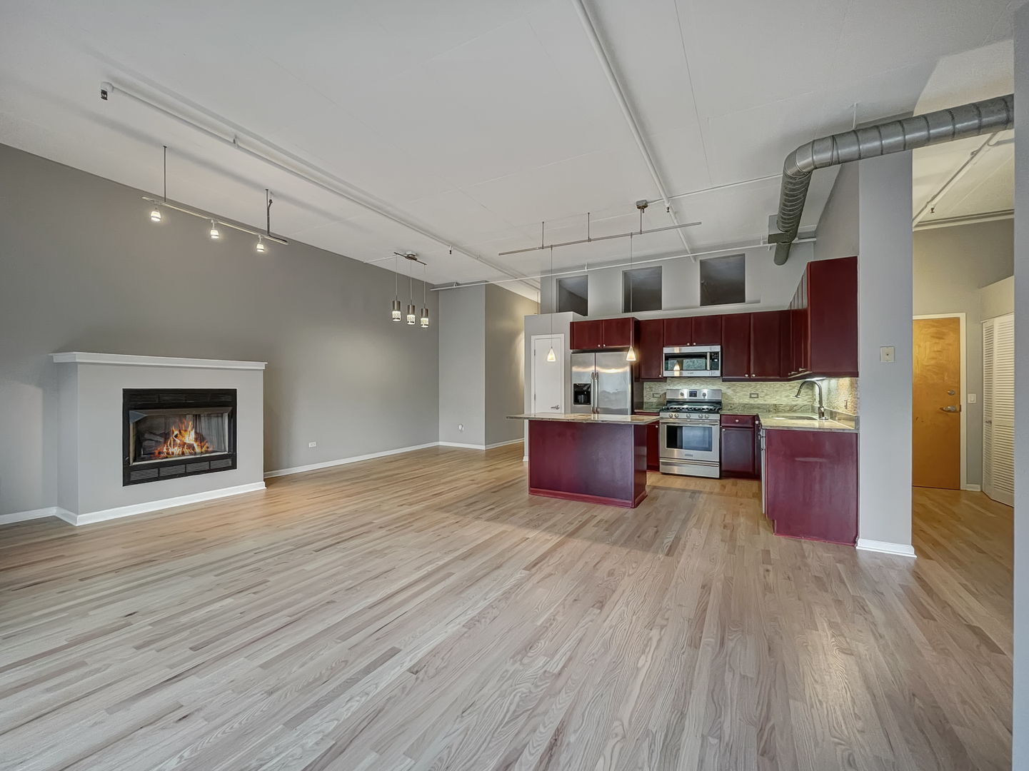 1301 West Madison Street, Unit 201 Chicago, IL 60607 - Photo 6 of 14 a kitchen with stainless steel appliances kitchen island wooden cabinets and fireplace