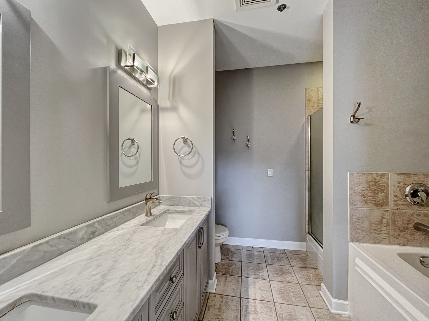 1301 West Madison Street, Unit 201 Chicago, IL 60607 - Photo 10 of 14 a spacious bathroom with a granite countertop sink a mirror and bathtub