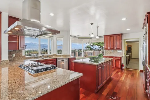 a kitchen with stainless steel appliances granite countertop a sink a stove and a wooden floors