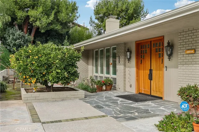 a view of a house with potted plants and a pathway