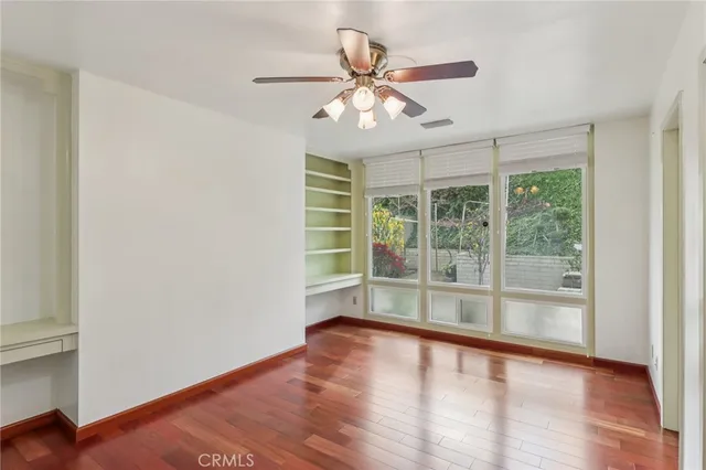 an empty room with wooden floor and ceiling fan