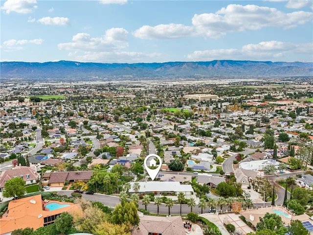 a view of a white house with a yard plants and large tree