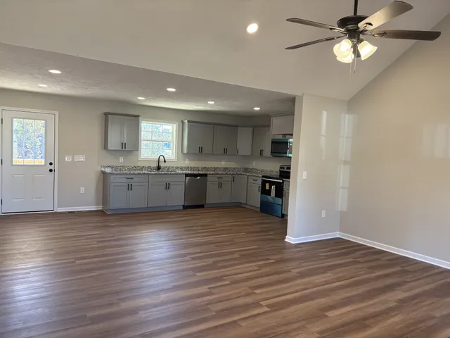 a view of kitchen and empty room with wooden floor