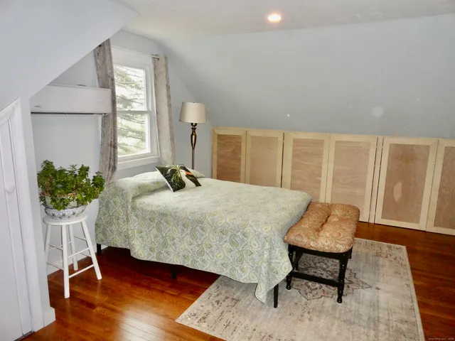 a bedroom with a bed and a potted plant on dresser