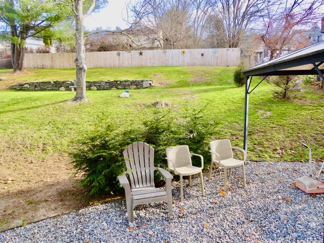 a view of a lake with table and chairs and wooden fence