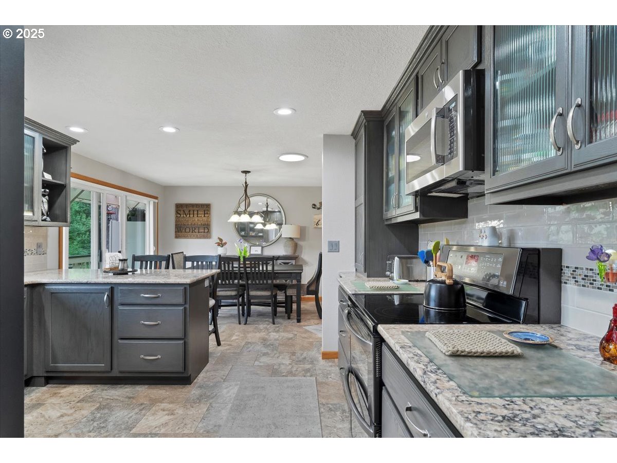 9076 Daleview Road Southeast Salem, OR 97317 - Photo 12 of 45 a kitchen with stainless steel appliances granite countertop a stove top oven a sink a dining table and chairs