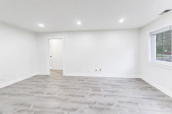 an empty room with wooden floor and a sink