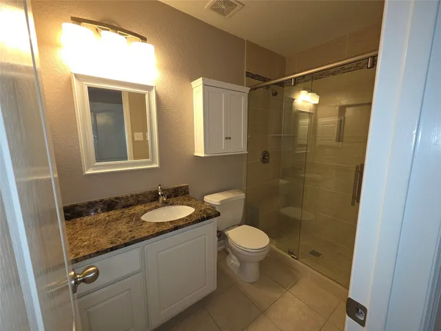 a bathroom with a granite countertop sink toilet and shower