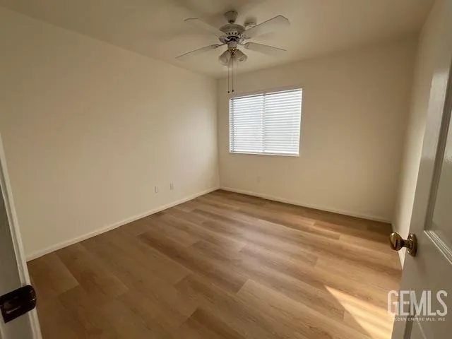 an empty room with a window and a ceiling fan