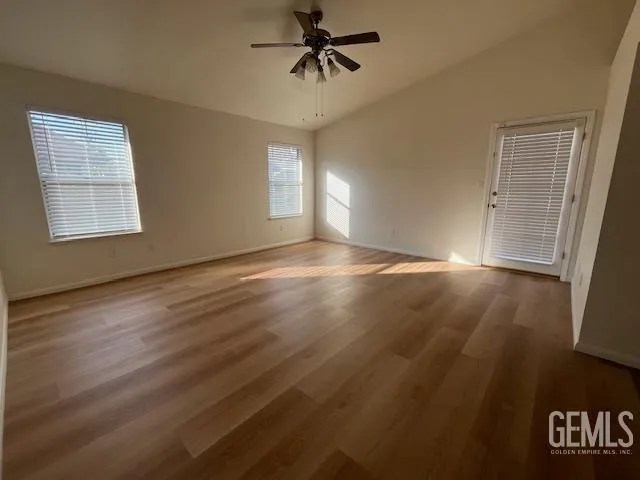 an empty room with wooden floor fan and windows