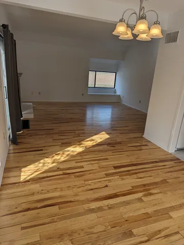 a view of a room with wooden floor and chandelier