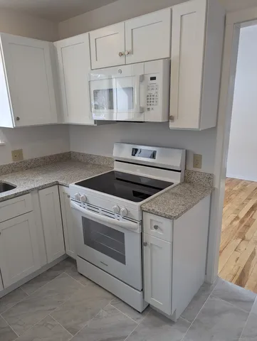 a view of a kitchen with white cabinets