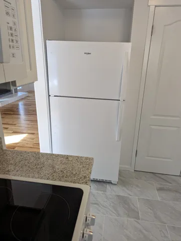 a view of a storage and utility room with refrigerator