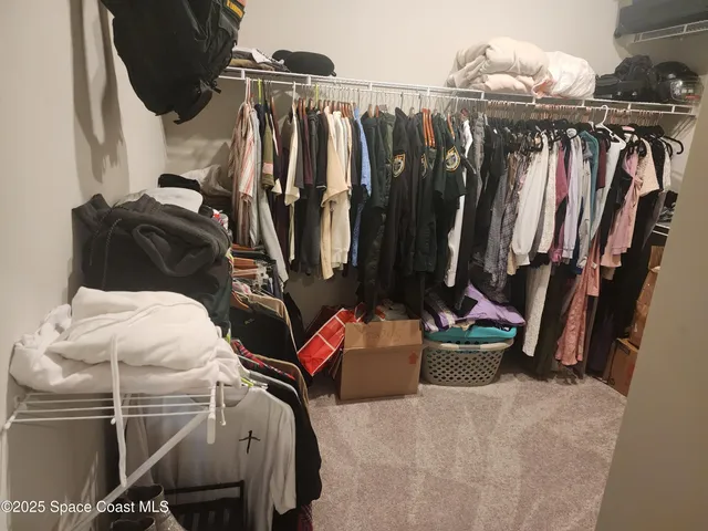 a view of walk in closet with clothes and shoes