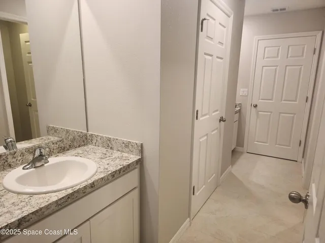a en suite bathroom with a granite countertop sink and a mirror