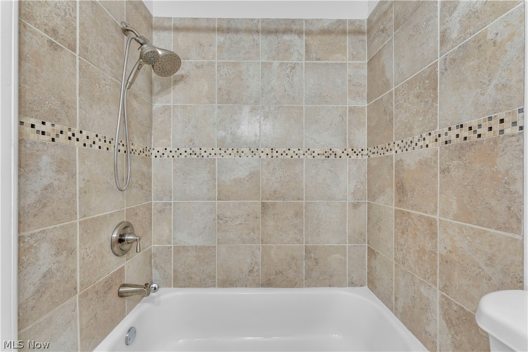 2540 Charney Road University Heights, OH 44118 - Photo 31 of 44 Bathtub with full-height tile surround, featuring an accent mosaic tile band and brushed nickel fixtures including a handheld showerhead