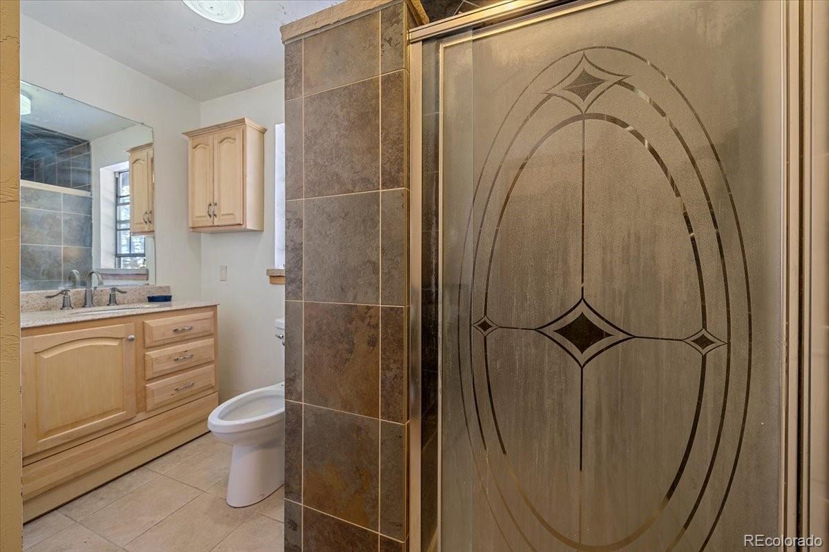 4551 Hilltop Road Evergreen, CO 80439 - Photo 11 of 30 a bathroom with a granite countertop sink toilet and shower