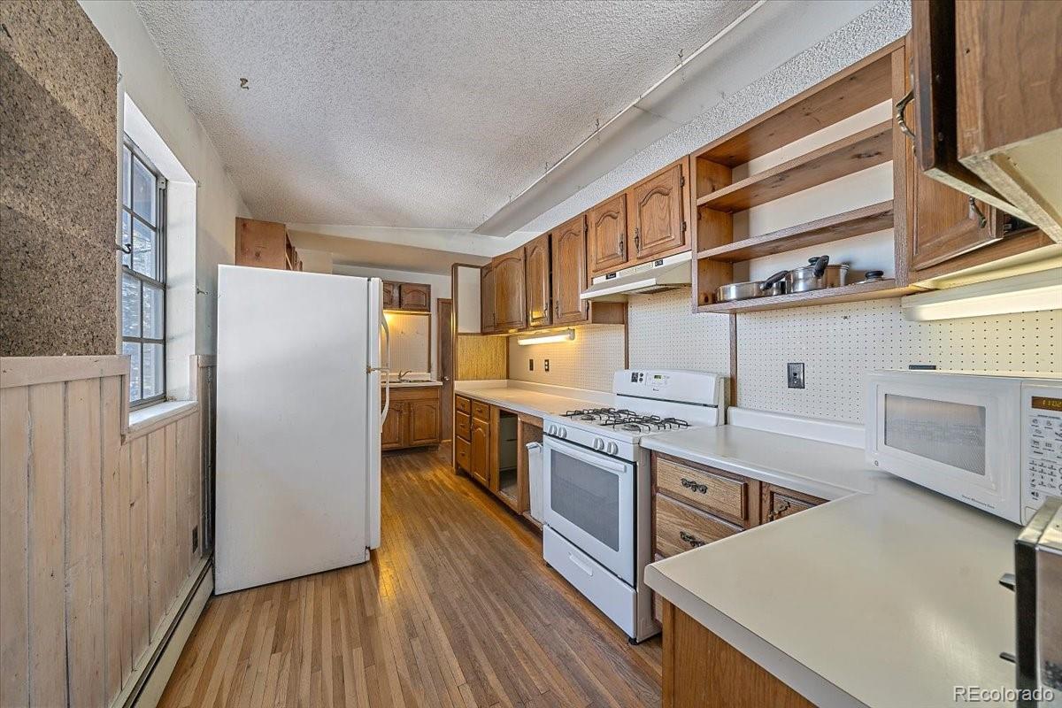 4551 Hilltop Road Evergreen, CO 80439 - Photo 7 of 30 a kitchen with stainless steel appliances granite countertop a refrigerator a stove and a wooden floors