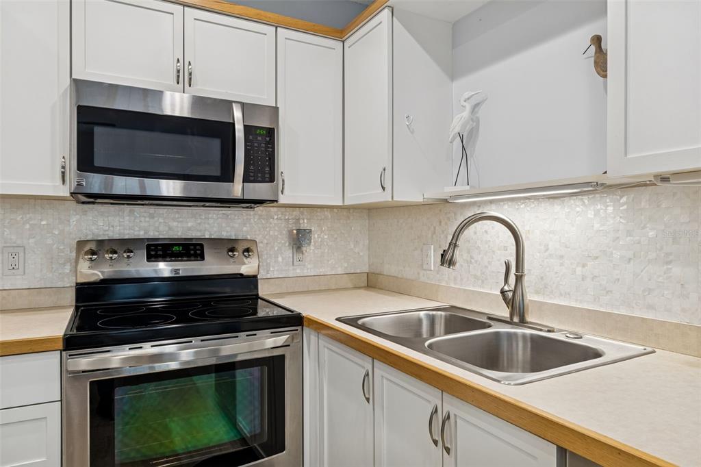 2291 Americus Boulevard West, Unit 3 Clearwater, FL 33763 - Photo 14 of 88 a kitchen with stainless steel appliances a stove a microwave a sink and cabinets