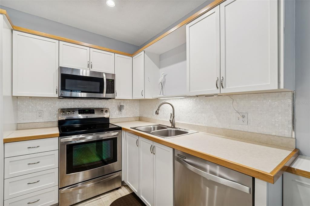 2291 Americus Boulevard West, Unit 3 Clearwater, FL 33763 - Photo 15 of 88 a kitchen with white cabinets stainless steel appliances and sink