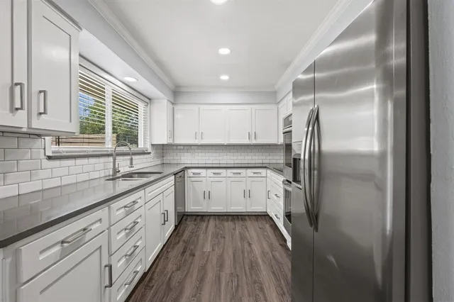 a kitchen with granite countertop stainless steel appliances a refrigerator sink and cabinets