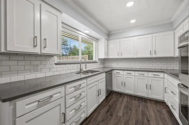 a kitchen with granite countertop white cabinets white appliances a sink and dishwasher with wooden floor