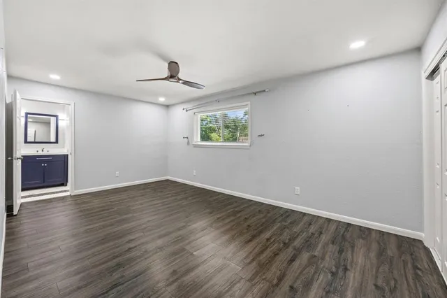 an empty room with wooden floor ceiling fan and windows