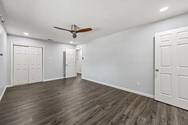 a view of empty room with wooden floor and ceiling fan